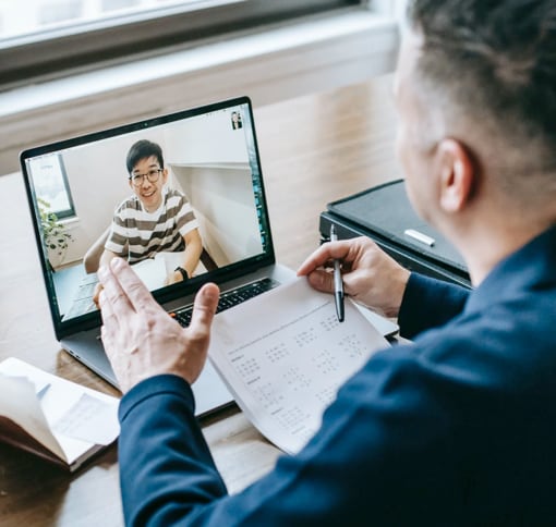 A men in a meeting with someone else using his laptop